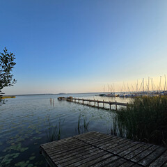 Fototapeta premium A Serene and Stunning Lakeside View at Sunset Featuring a Pier and a Clear Sky Above