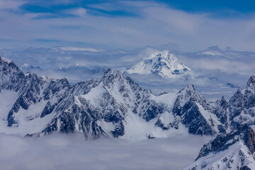 Naklejka premium Snow and glacier in the high mountains in the Alps. View of the alpine scenic landscape of rocky summit peaks and glacier ice crevasse from the top of the mountain Aiguille du Midi cable car Chamonix