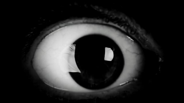 Extreme close-up, forward motion, of human eye in haunting black and white with dilated pupil, never blinking. Unsettling film noir mood with dramatic shadows. Psychological thriller, surveillance.
