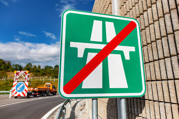 Highway exit, road sign "end of highway". Work on road in background