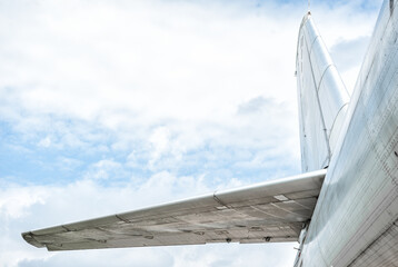 Close-up of airplane tail and wing with cloudy sky backdrop