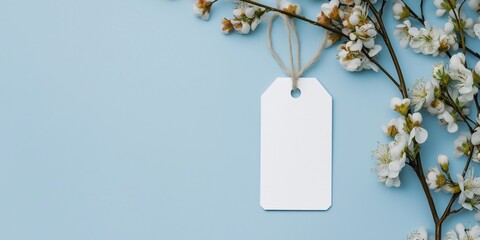 A white tag is hanging from a branch of a tree. The tag is blank, and the image is of a blue background