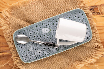 Empty ceramic cups with jute napkin on ceramic tray on wooden table, close-up, top view.