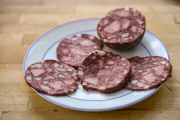 Slices of blood sausage or black pudding on a plate and a rustic wooden table, selected focus