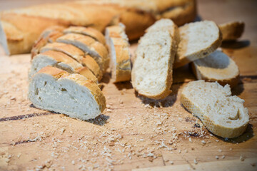 Fresh baguette or French bread cut into slices on a wooden kitchen board, selected focus