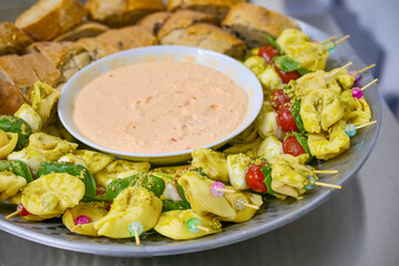 Tortellini skewers with tomato mozzarella and basil and a dip served with bread on a bowl, finger food for a party buffet, selected focus,
