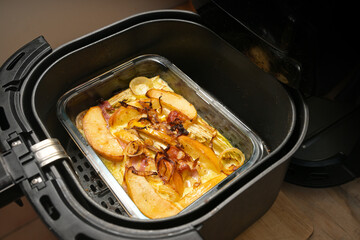Casserole from chicory, apple, onion and bacon in cheese bechamel sauce in an ovenproof glass dish baked in the black hot air fryer, copy space, selected focus