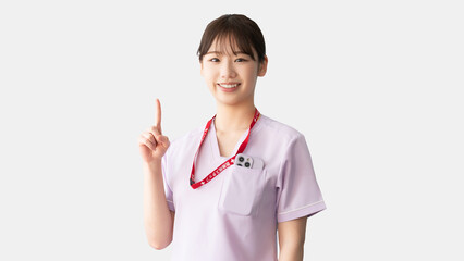人差し指を立てて案内する女性医療スタッフ