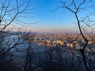 View of urban landscape from a hilltop during early evening with city lights beginning to shine