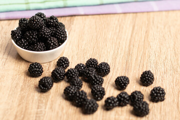 moras en un plato de cerámica junto a varias moras sobre una mesa
