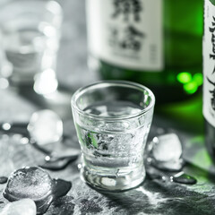 Close-up of soju glass with ice on textured surface  