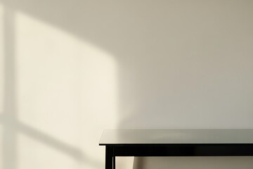 A minimal interior with a black table and a bright wall, sunlight casting shadows.