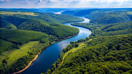 Fototapeta premium Aerial View of a Winding River Through a Valley - A breathtaking drone perspective of a winding river cutting through lush green valleys