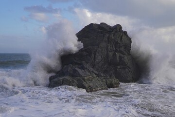 A powerful storm rages across the sea. Enormous waves crash against jagged rocks. The wind howls,...
