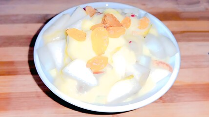 A bowl of homemade fruit custard with fresh apples, pears, bananas, and raisins, topped with creamy custard. A perfect blend of textures and flavors for a refreshing and delightful dessert.

