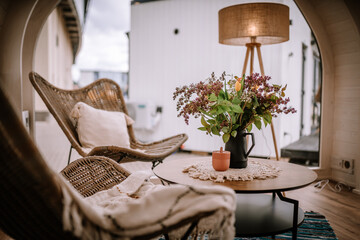 Cozy seating area with wicker chairs, soft pillows, a wooden table with a floral arrangement, and a...