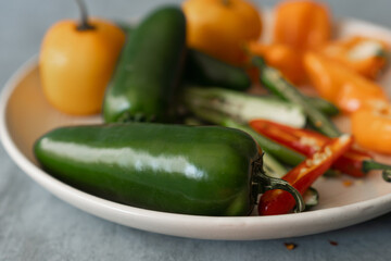 jalapeño chilli on a plate with a variety of chillies, habanero, red, arbol, etc. 