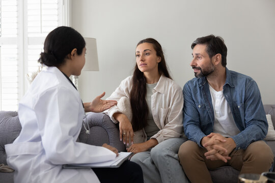 Serious young couple visiting female doctor, consulting about healthcare problems, consulting medical professional, discussing recommendation, treatment, diagnosis