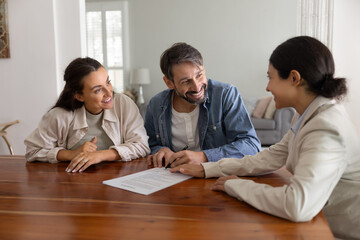 Happy husband and wife meeting with realtor, financial broker, adviser, signing legal paper...