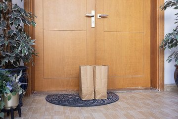 Paper bags from grocery store waiting for recipient on floor doormat. Craft packets leaved by...