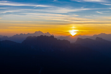 Sunset silhouette of the mountains in the Alps. Dolomites alpine beautiful landscape in red, orange and yellow light of sunset and sunrise, dawn soft light through darkness of the sky in the Dolomiti