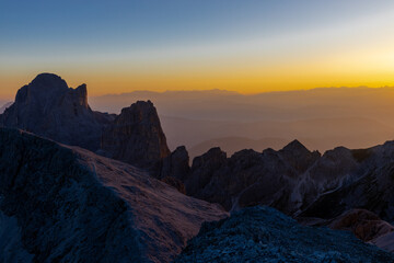 Sunset silhouette of the mountains in the Alps. Dolomites alpine beautiful landscape in red, orange and yellow light of sunset and sunrise, dawn soft light through darkness of the sky in the Dolomiti