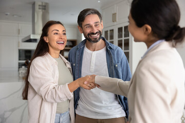 Accommodation rent agent and couple of tenant shaking hands in apartment, smiling, laughing,...