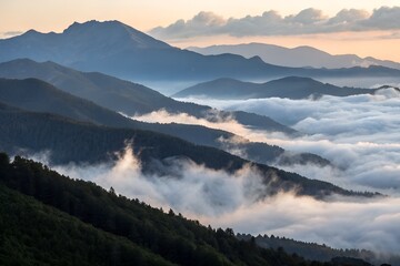 Obraz premium Fog rolling over a mountain range at dawn.