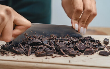 Dark chocolate being chopped on wooden cutting board