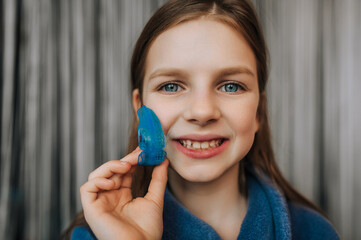 Close-up photo, portrait of beautiful happy smiling girl child teenager face with blue silicone...