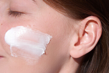 Beauty skincare close up portrait of a young woman with moistunizer on her face. Domestic skin care treatments.