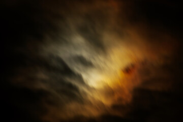  surreal night sky with an intense glow behind dark, swirling clouds. The dramatic mix of warm and...
