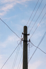 A lot of electrical wires, live cables connecting on a pole against the sky.