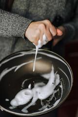 A housewife woman washes a Teflon frying pan in the kitchen with a yellow sponge and foam detergent.