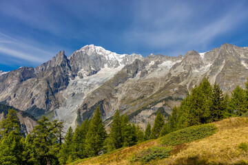 Obraz premium Beautiful mountain landscape of the Alps in summer on tour du Montblanc area near Courmayeur village in Val Ferret valley in Italy. European Alps stunning views of green valley with colorful flowers