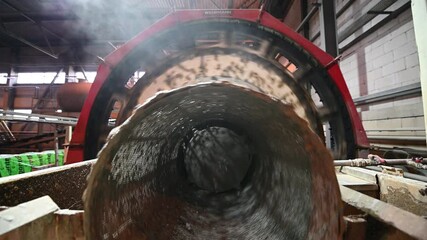 Output end of ball mill with mineral in drum at plant