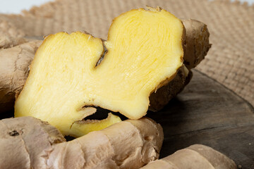 Fresh organic ginger rhizome root used in traditional medicines and for flavoring meals, drinks, on wooden board