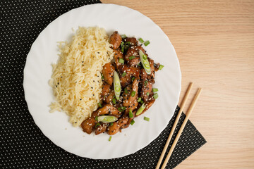 Sweet and sour fried chicken with steamed rice and spring onions - flat lay top view, horizontal image. Sesame Chicken Asian Style.
