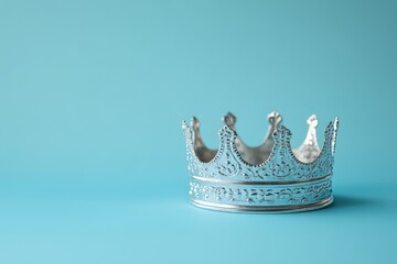 A decorative silver crown sits on a bright blue surface