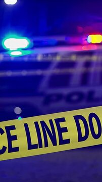 Vertical screen, police emergency lights blinking red, blue, white behind yellow caution tape, revealing nighttime law enforcement crime scene investigation tension