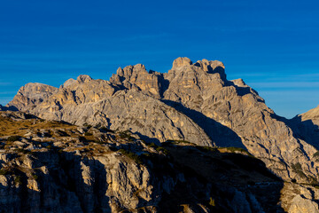 Fototapeta premium Dolomite Alps mountains in Europe beautiful landscape photo. Stunning rocky peaks of Dolomiti Alps under clear blue sky cliffs and climbing walls of European Alps scenic view