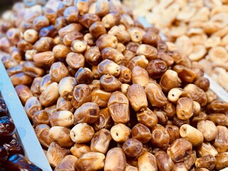 Ripe dark dates are laid out on a tray for sale in a supermarket with an emphasis on the rich quality and color of dried fruits. Close-up