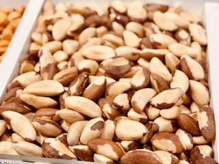 Close-up of a large number of Brazil nuts offered for sale in a box at a local specialty market. Close-up