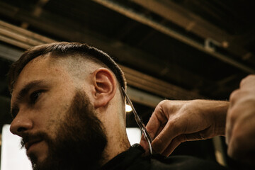 Barbershop. Unrecognizable male barber hands making customer Fashionable haircut in Modern style...