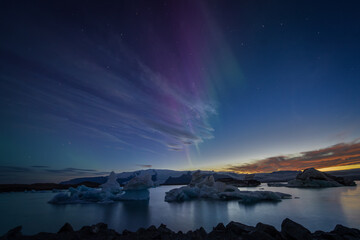 Stunning aurora borealis glowing in vivid green and purple shades over a wintery Arctic landscape at night at icy Jökulsárlón glacier lagoon in Iceland at night.
