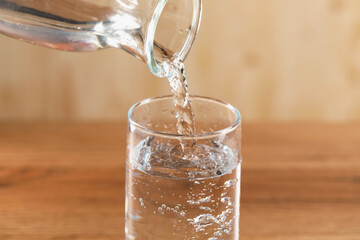 Pouring refreshing soda water into glass against blurred background, closeup