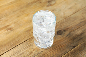 Refreshing soda water with ice cubes in glass on wooden table, closeup