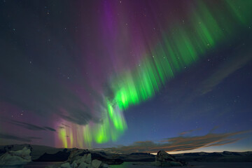 Stunning aurora borealis glowing in vivid green and purple shades over a wintery Arctic landscape...