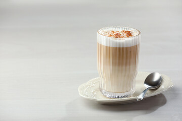 Tasty latte macchiato in glass on white table, space for text. Coffee drink