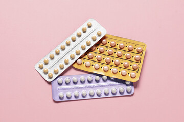 Blisters of oral contraceptive pills on pink background, flat lay